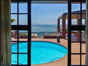 A view of a swimming pool with a clear blue ocean and distant mountains. - Cozy house with upscale furnishings and great views of the mountains and sea (Mountainside)