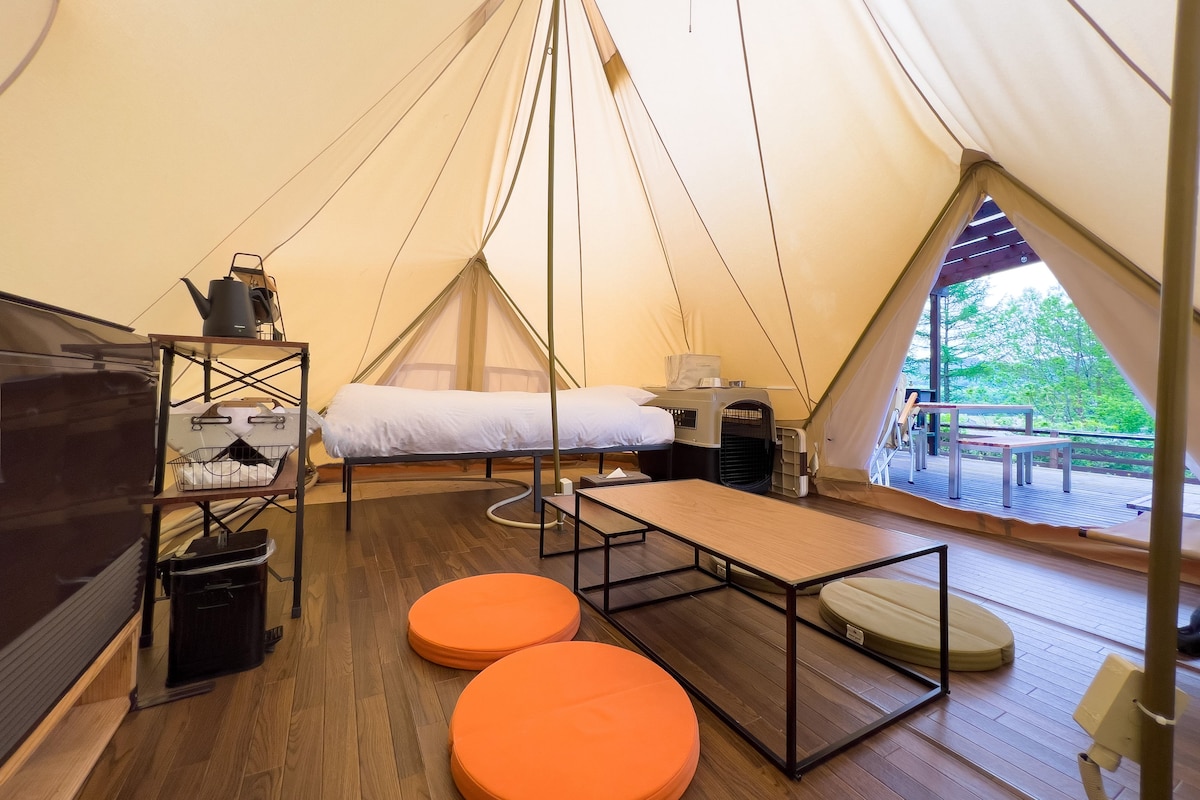 Una carpa con una cama, una mesa y asientos naranja.