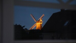 Un molino de viento al anochecer, con la silueta de un edificio en primer plano.