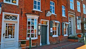 Un edificio tradicional de ladrillo con varias ventanas y puertas, algunas con contraventanas. Hay letreros que indican la presencia de un pub y un restaurante.