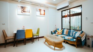 Ein Wohnzimmer mit einer Couch, Sesseln, einem Glastisch und Kunstwerken an den Wänden.