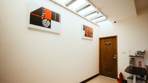 Ein Flur mit Kunstwerken an den Wänden, einer Holztür mit der Bezeichnung „301“ und einem kleinen Tisch mit Körben.