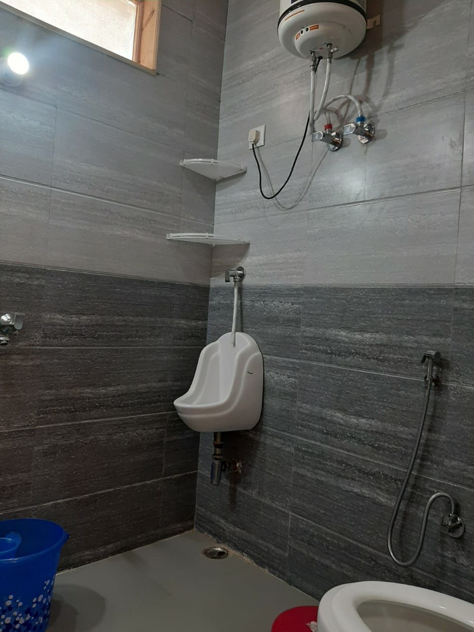 A bathroom with a urinal, a shower, and a toilet.