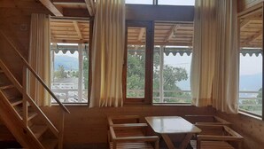 A wooden cabin with a dining area, a staircase, and large windows offering a view of the outdoors. - Snow View Luxury Homes (Dhari)