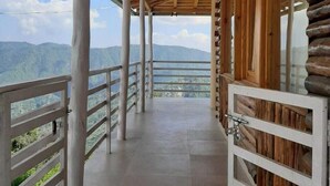 A wooden corridor with a tiled floor, white railings, and a view of mountains in the distance. - Snow View Luxury Homes (Dhari)