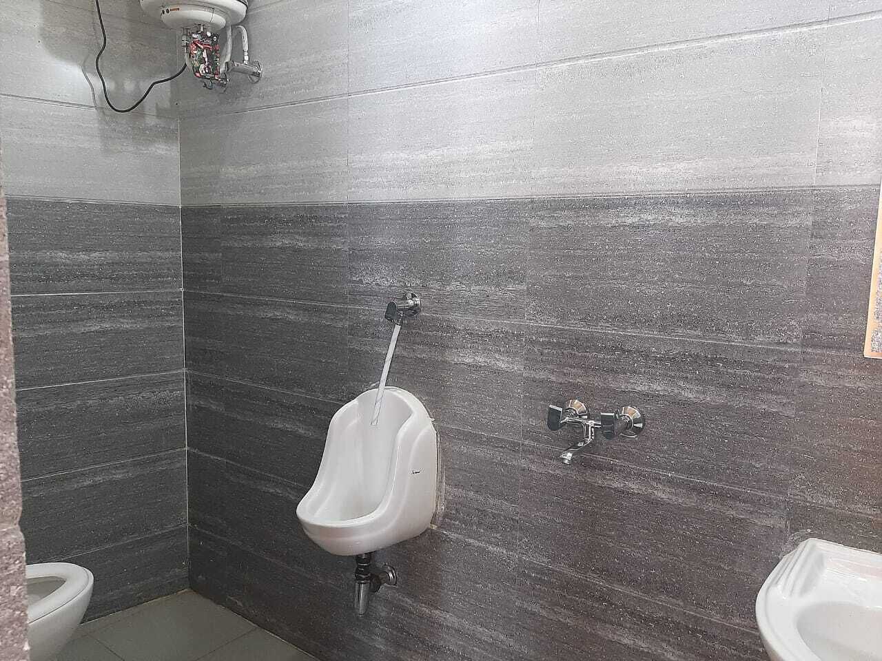 A men's restroom with a urinal, a toilet, and a wall-mounted faucet.