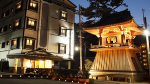 A traditional Japanese building with a wooden pagoda-style structure, adjacent to a modern multi-story residential building. - Arima Royal Hotel (Kobe)