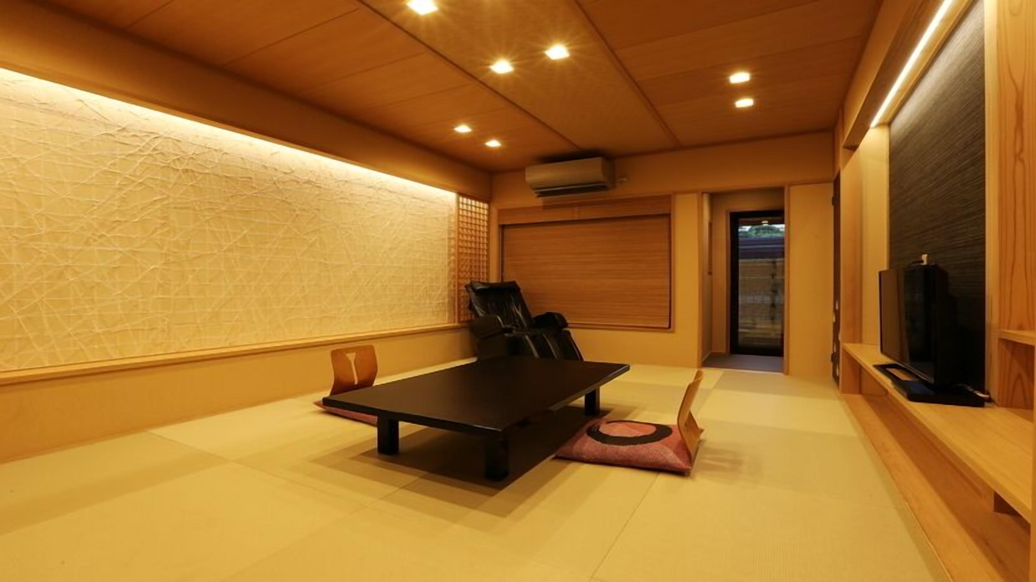 A room with a wooden floor, a black table, a black chair, a television, and a sliding door.