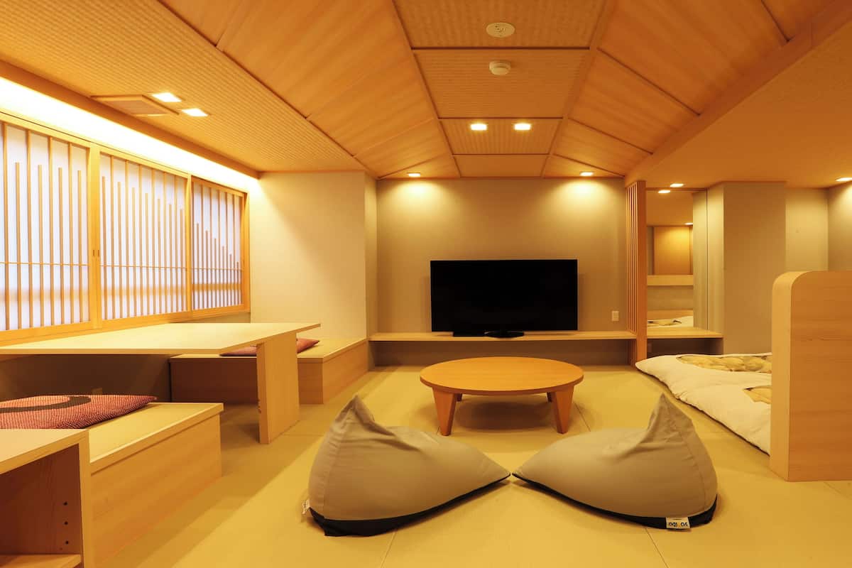 A modern interior with a flat-screen TV, wooden furniture, and a tatami mat floor.