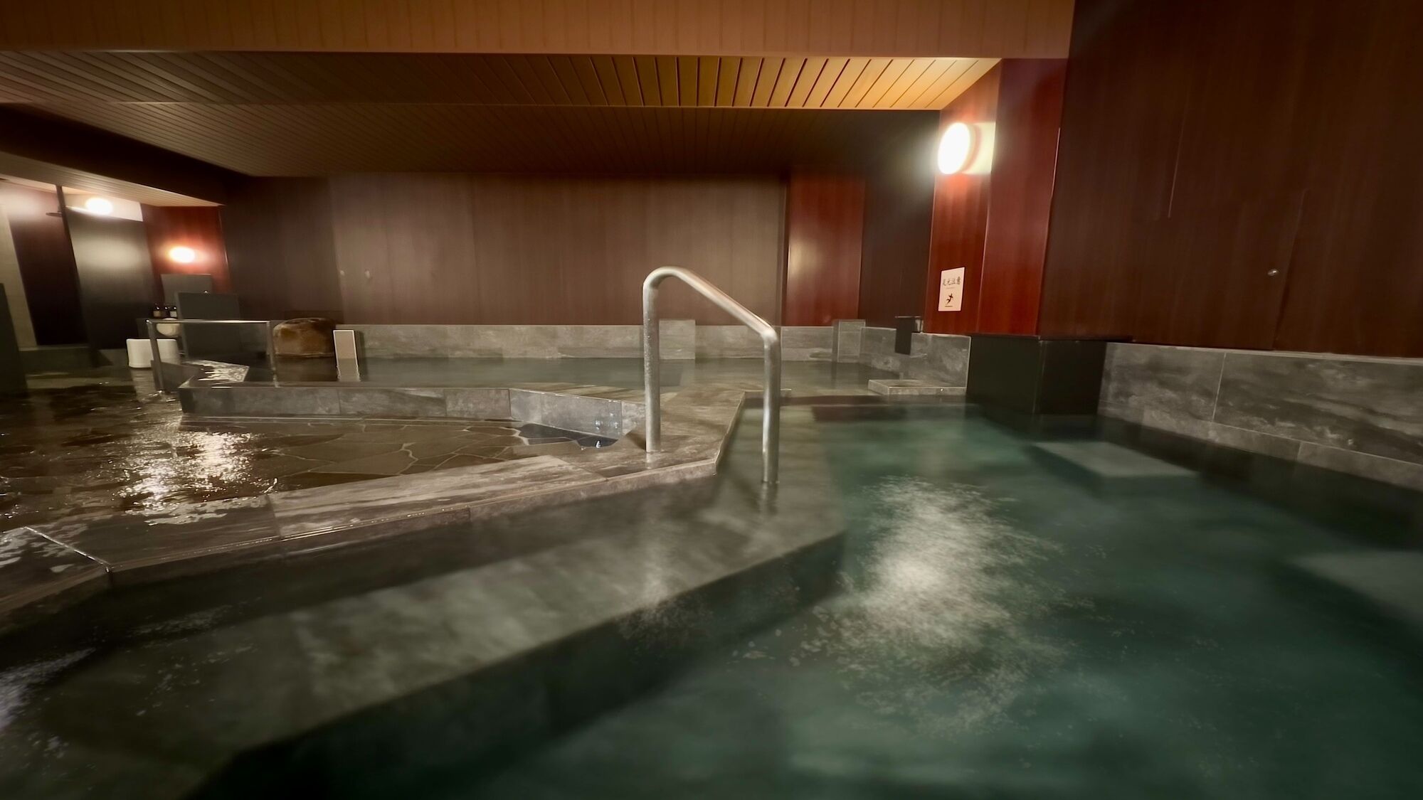 A spa area with a hot tub, a metal ladder, and a wooden ceiling.