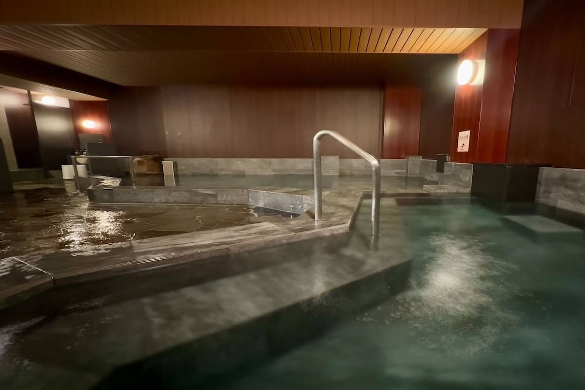 A spa area with a hot tub, a metal ladder, and a wooden ceiling.
