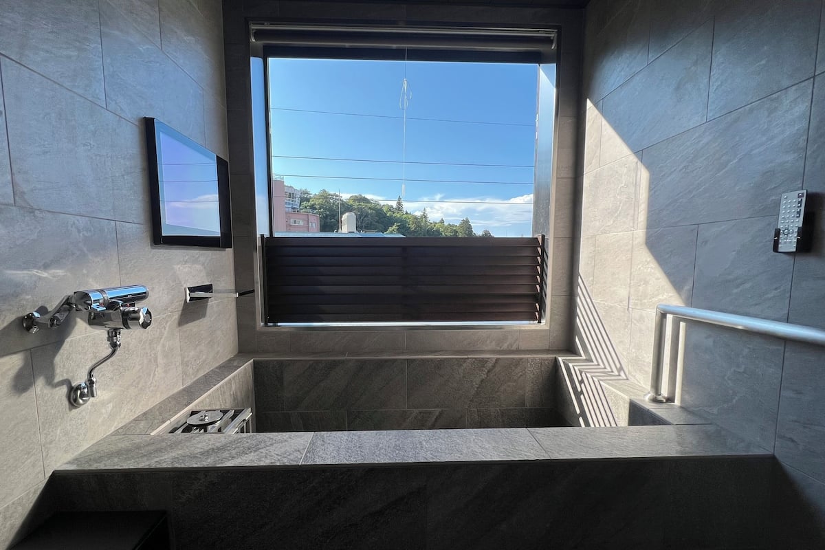A modern bathroom with a built-in sink, a window with a view of the outside, and a towel rack.