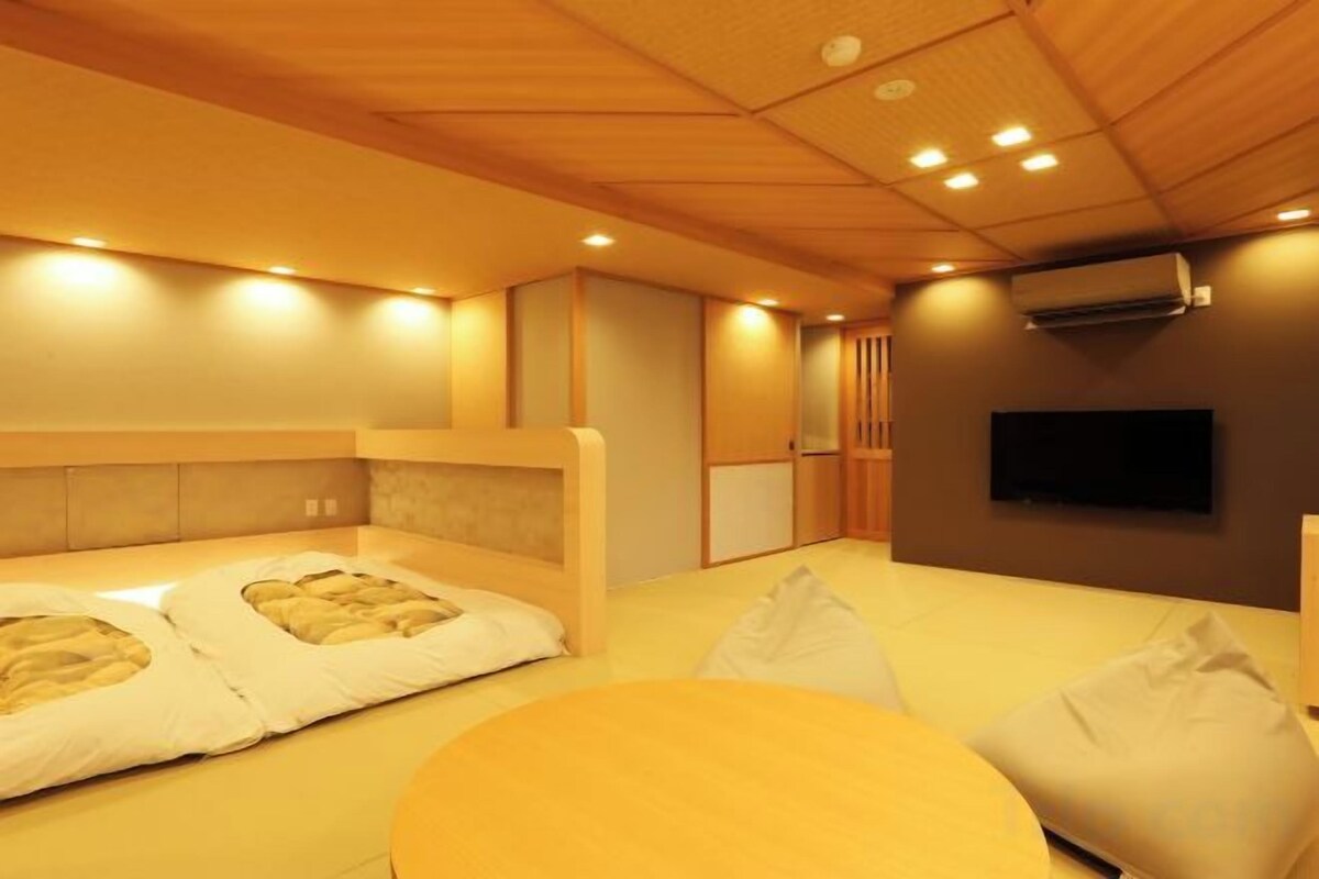 A room with a bed, a television, and a wooden ceiling.