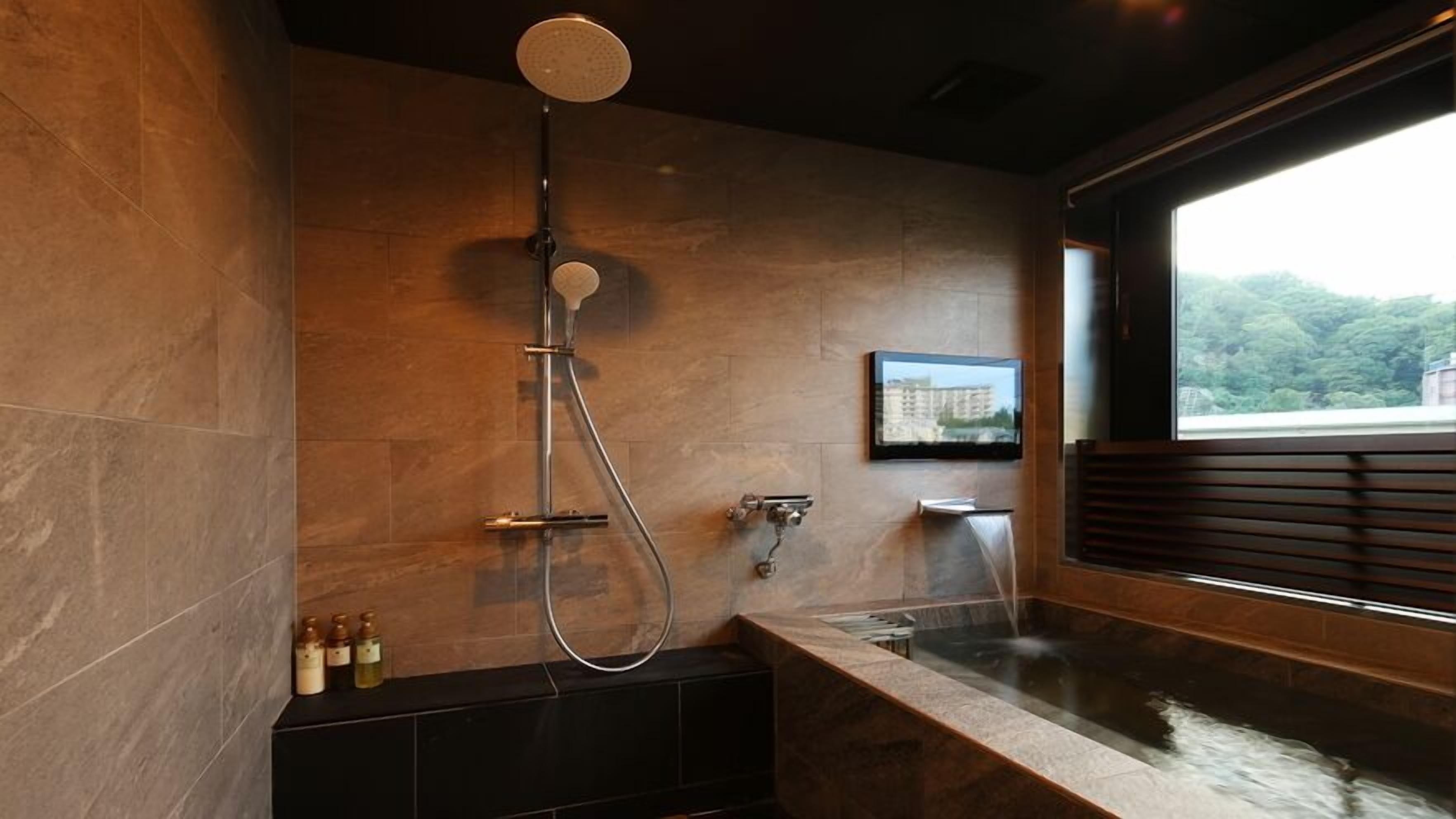 A modern bathroom with a bathtub, a shower, and a window with a view of greenery.
