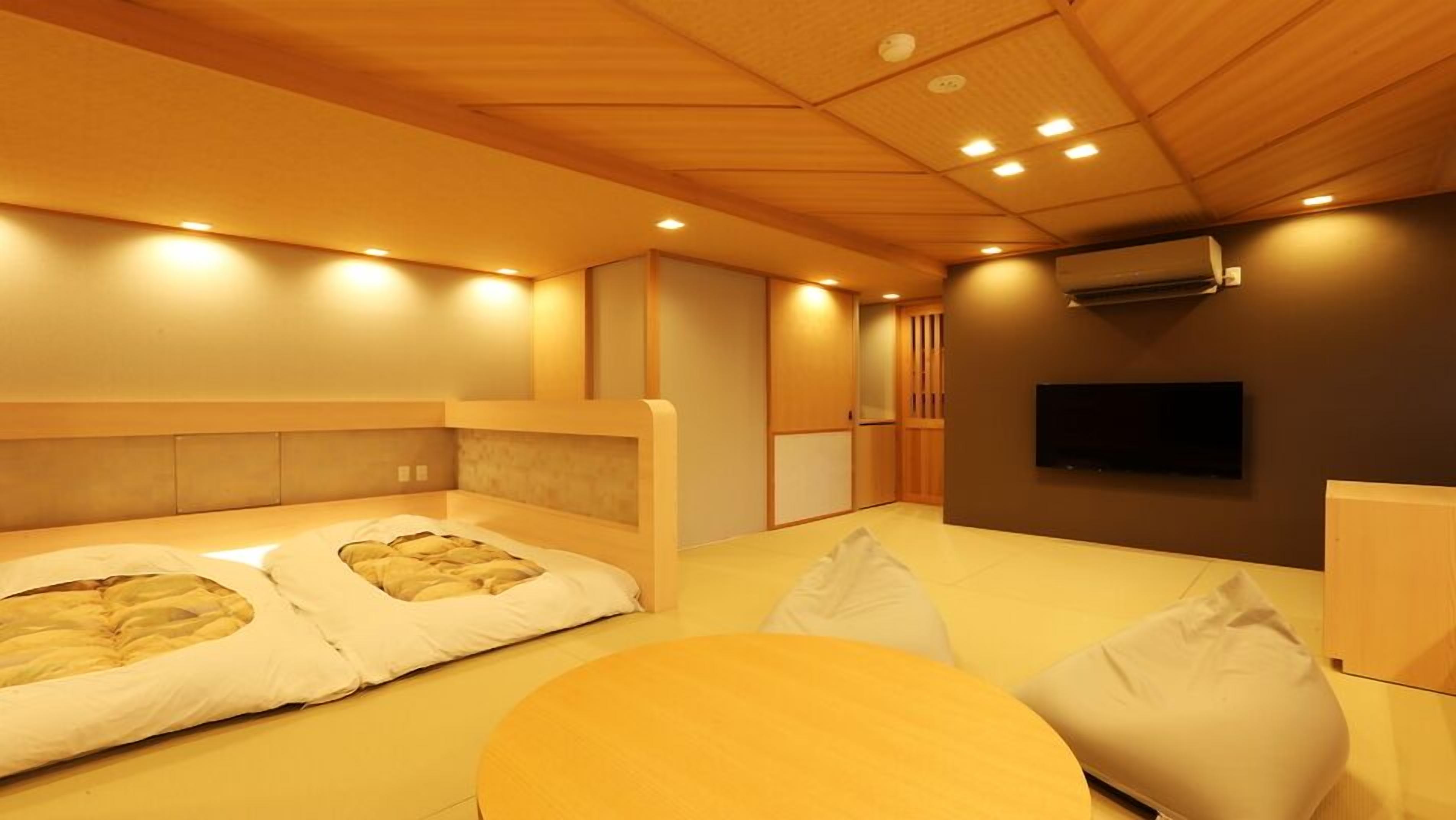 A modern hotel room with a large bed, a TV, and a small table.