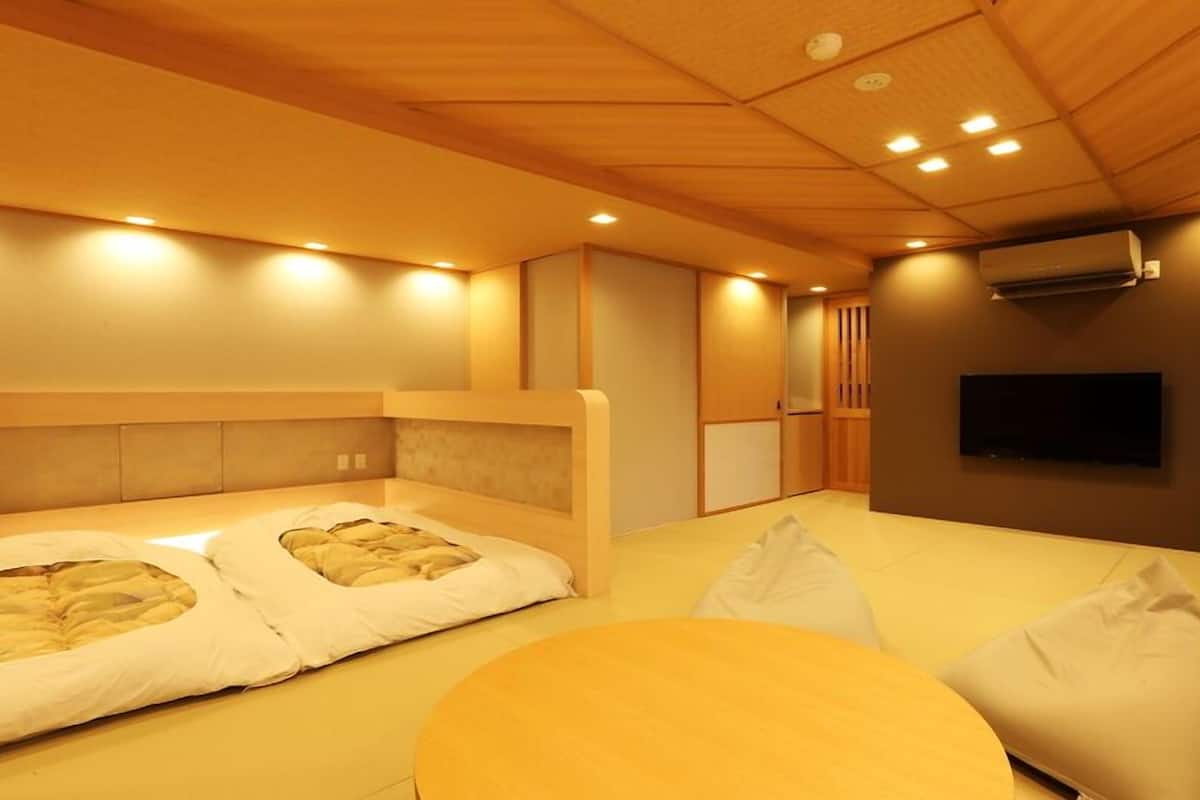 A modern hotel room with a large bed, a TV, and a small table.