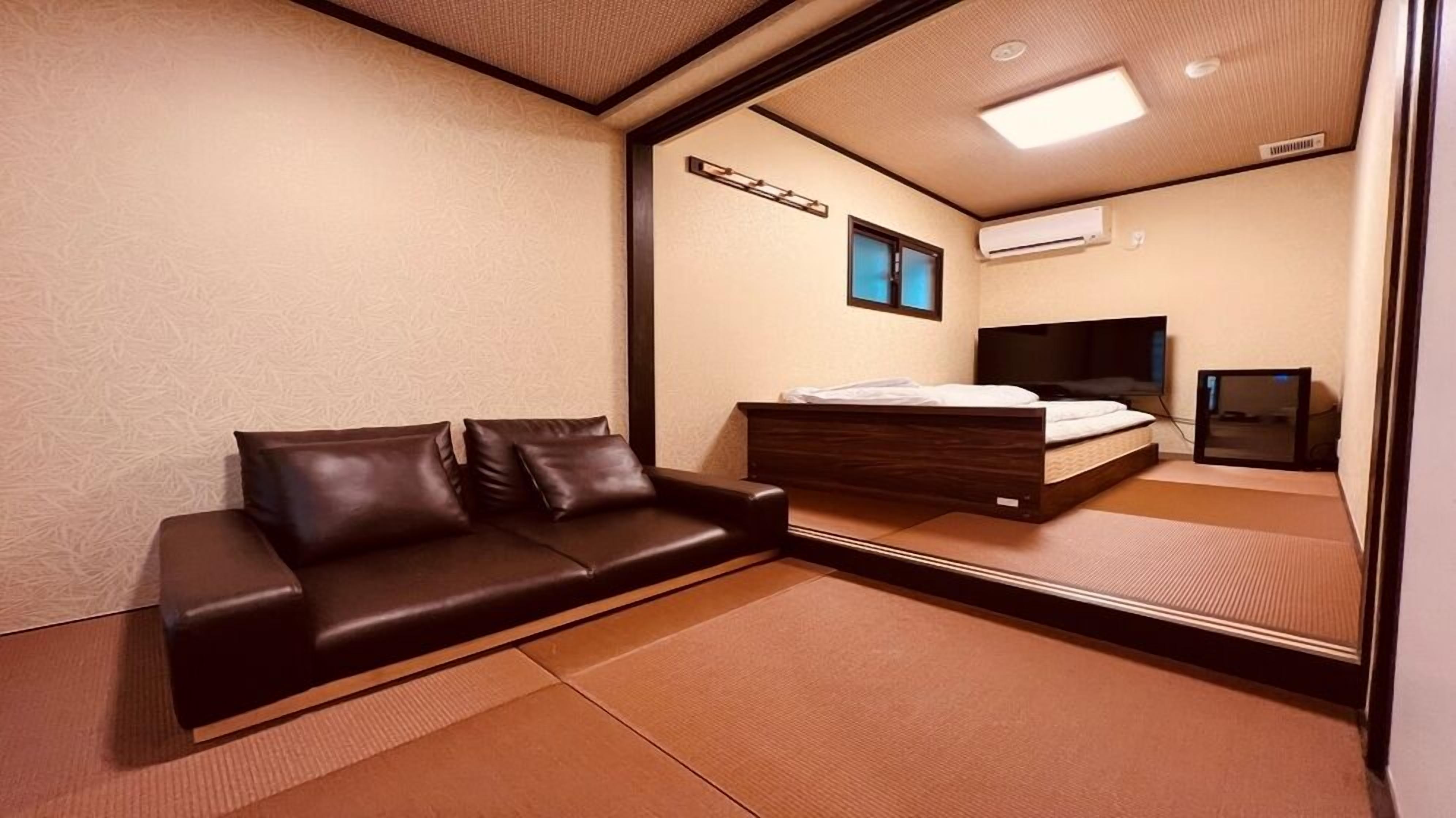 A room with a sofa, a bed, a television, and a mirror.