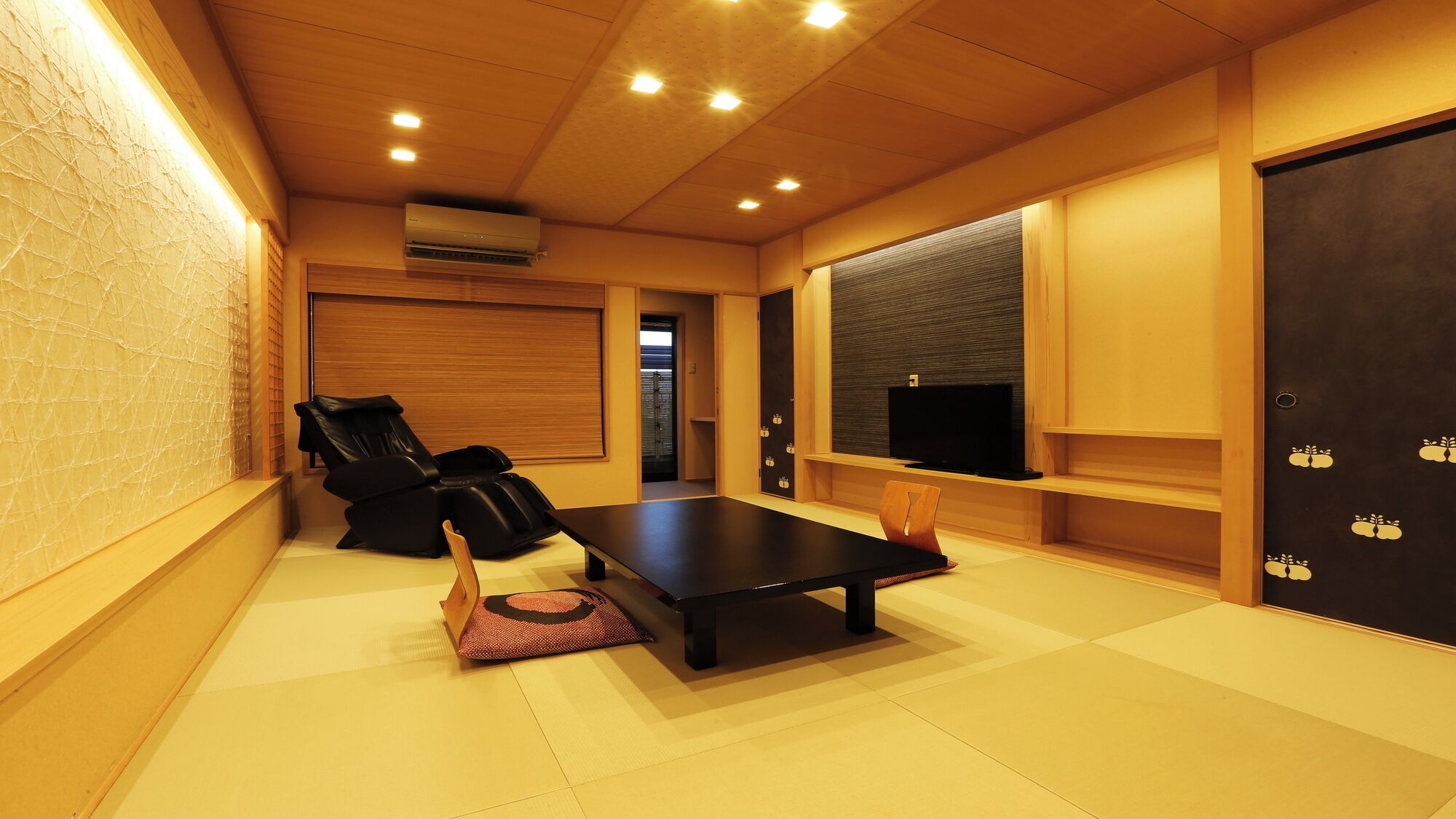 A room with a massage chair, a flat-screen TV, and a wooden floor.