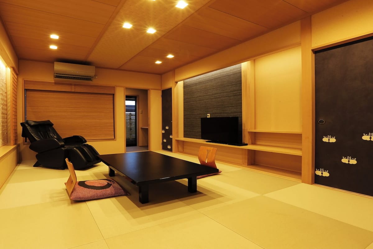 A room with a massage chair, a flat-screen TV, and a wooden floor.