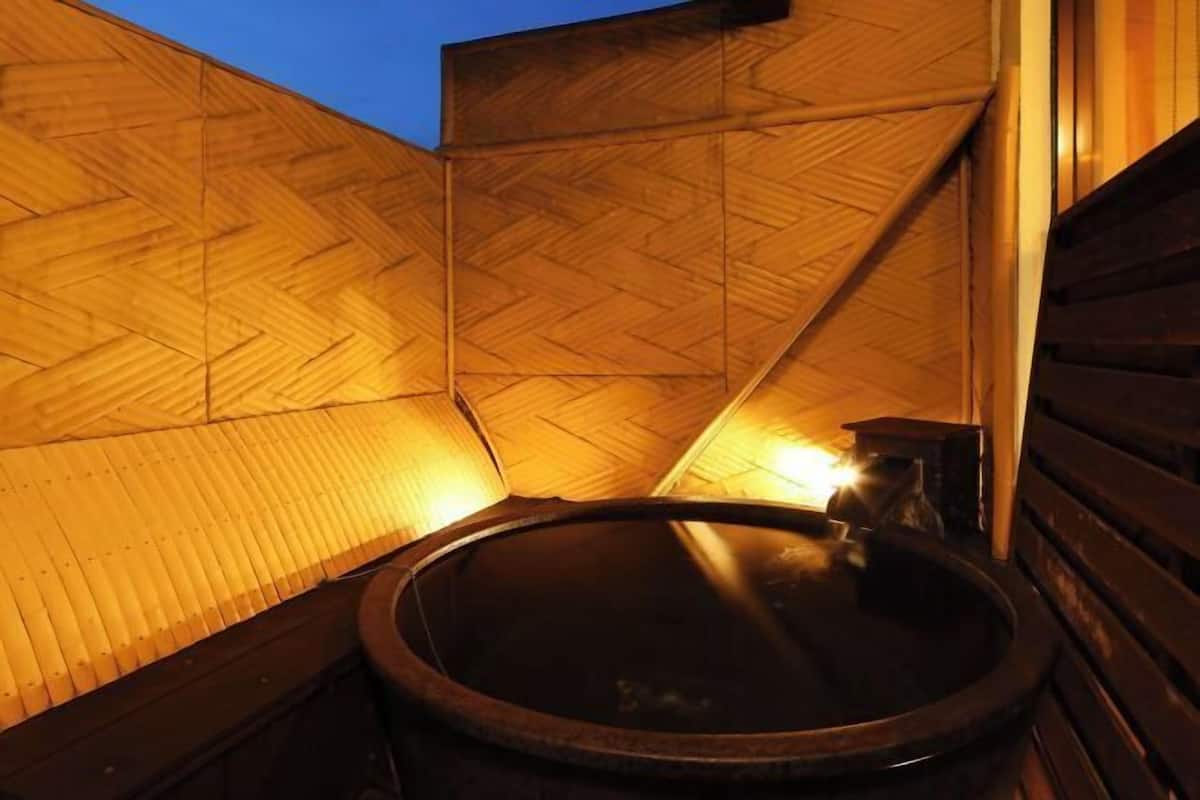 A wooden sauna with a circular hot tub, wooden walls, and a sloped ceiling.