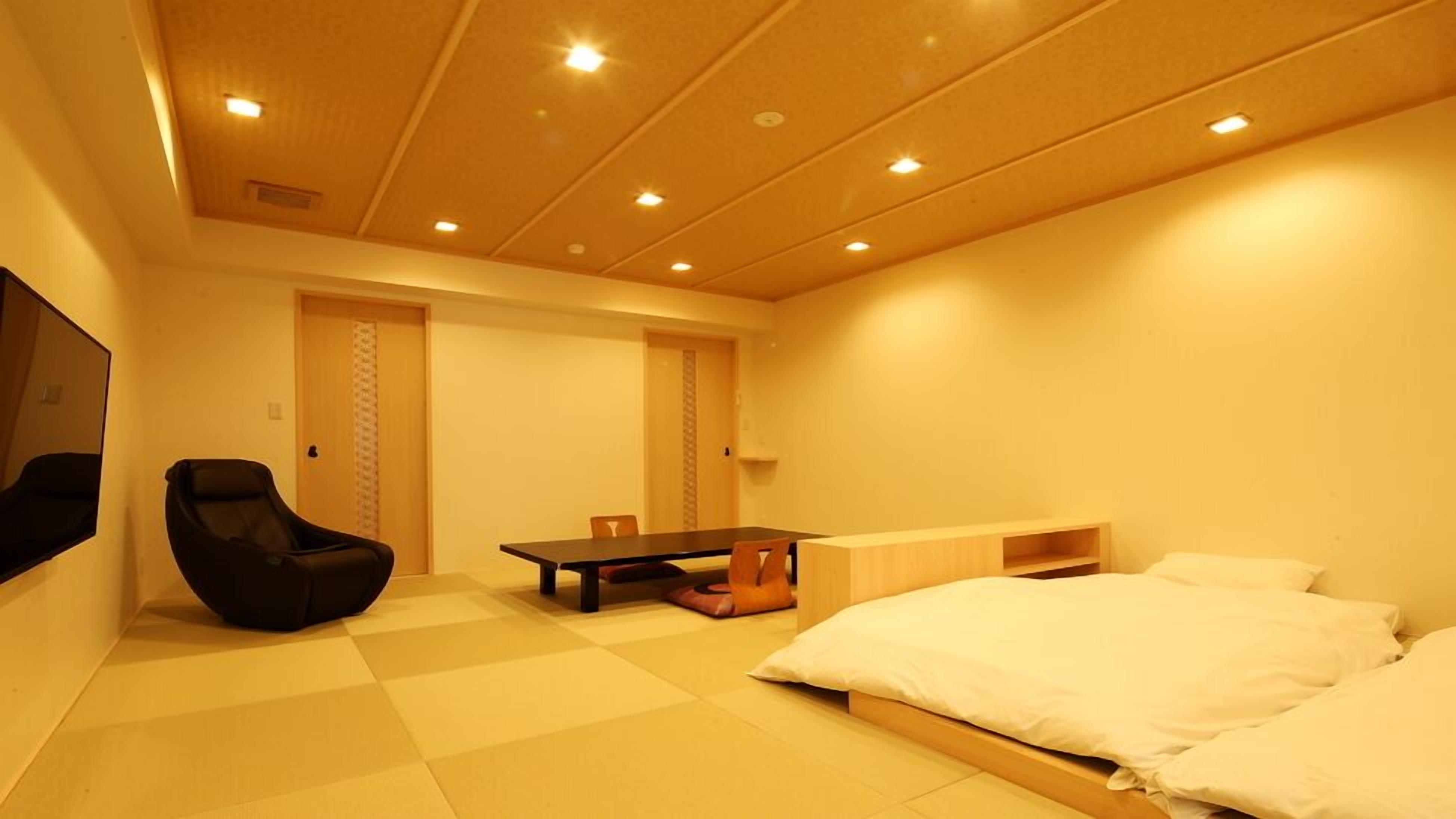 A hotel room with a bed, a chair, a table, and a TV.