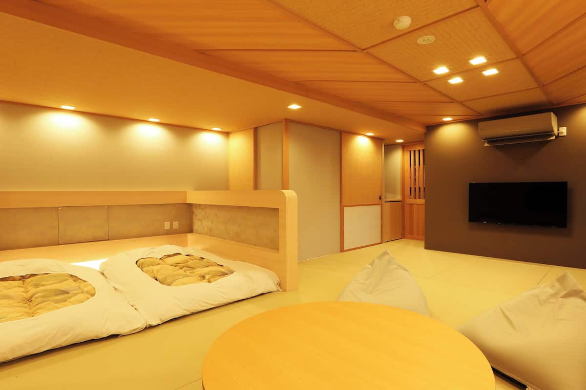 A room with two beds, a TV, and an air conditioning unit.