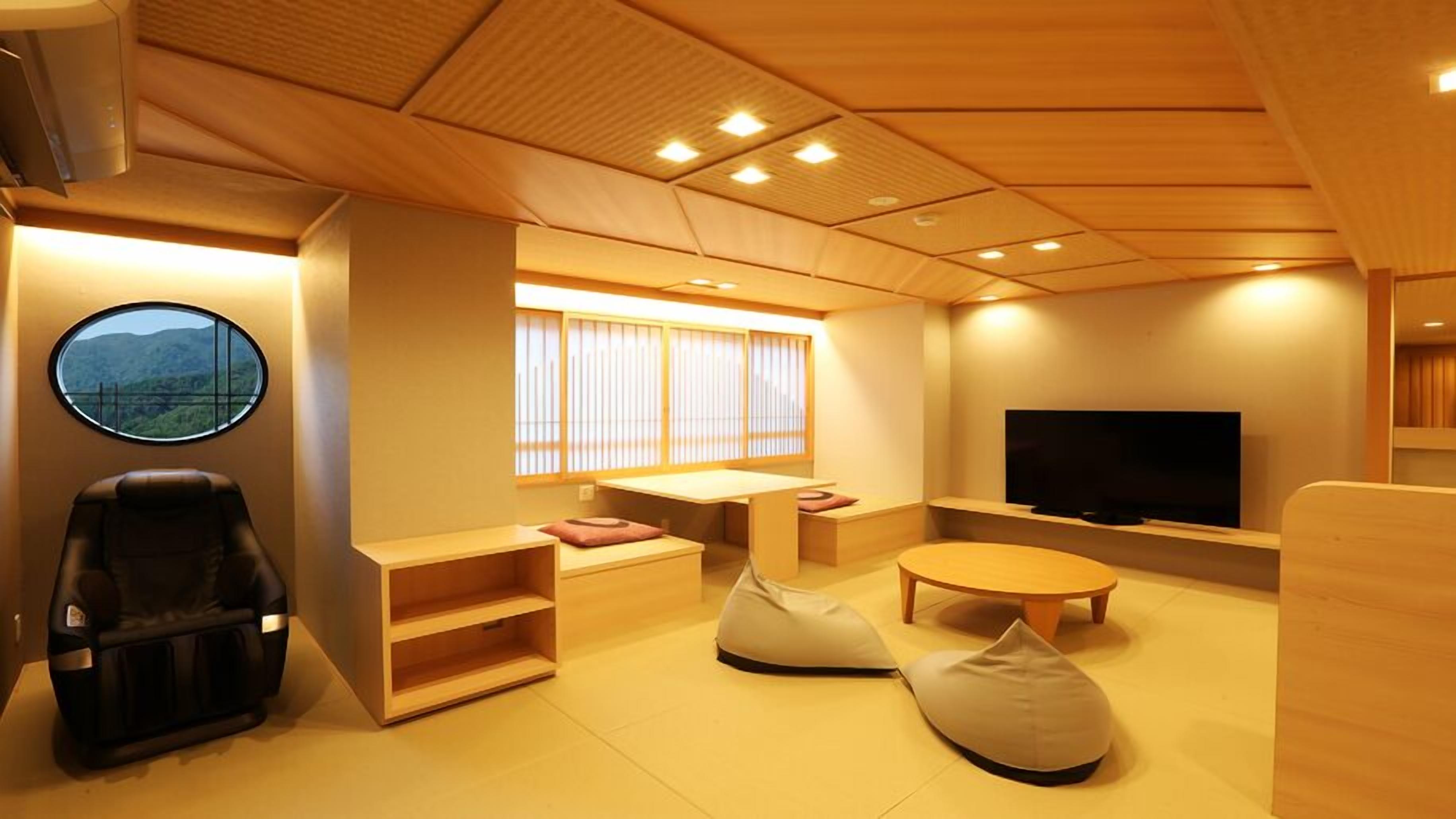 A modern living room with a sofa, ottoman, TV, and a window with blinds.