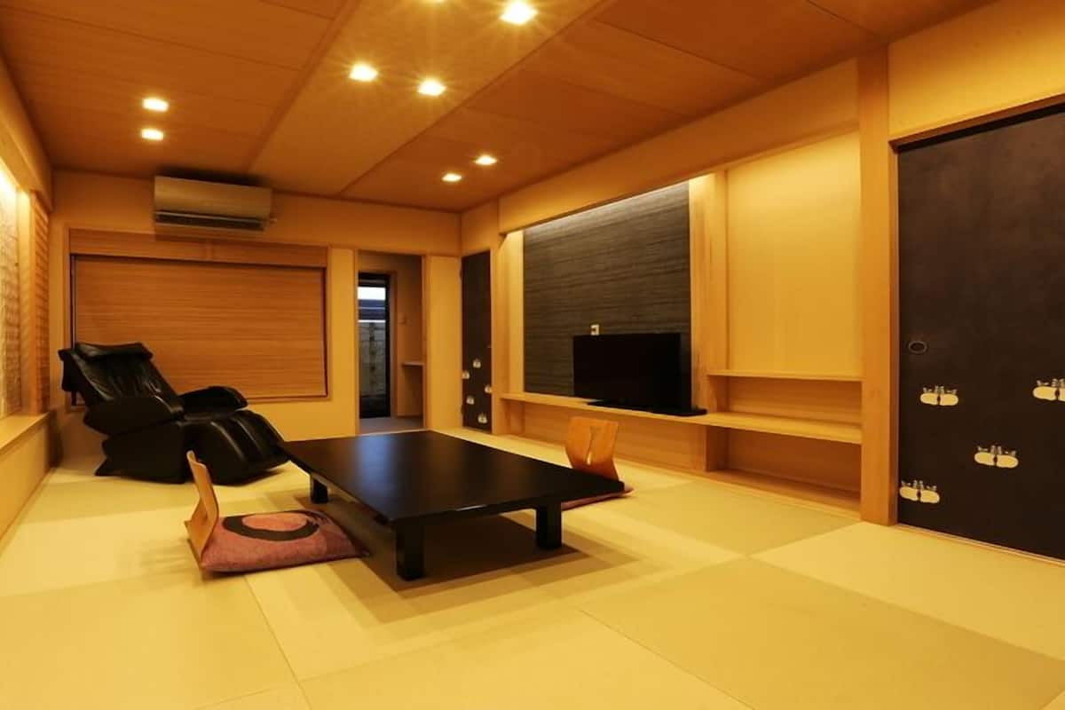 A room with a massage chair, a flat-screen TV, and a wooden floor.
