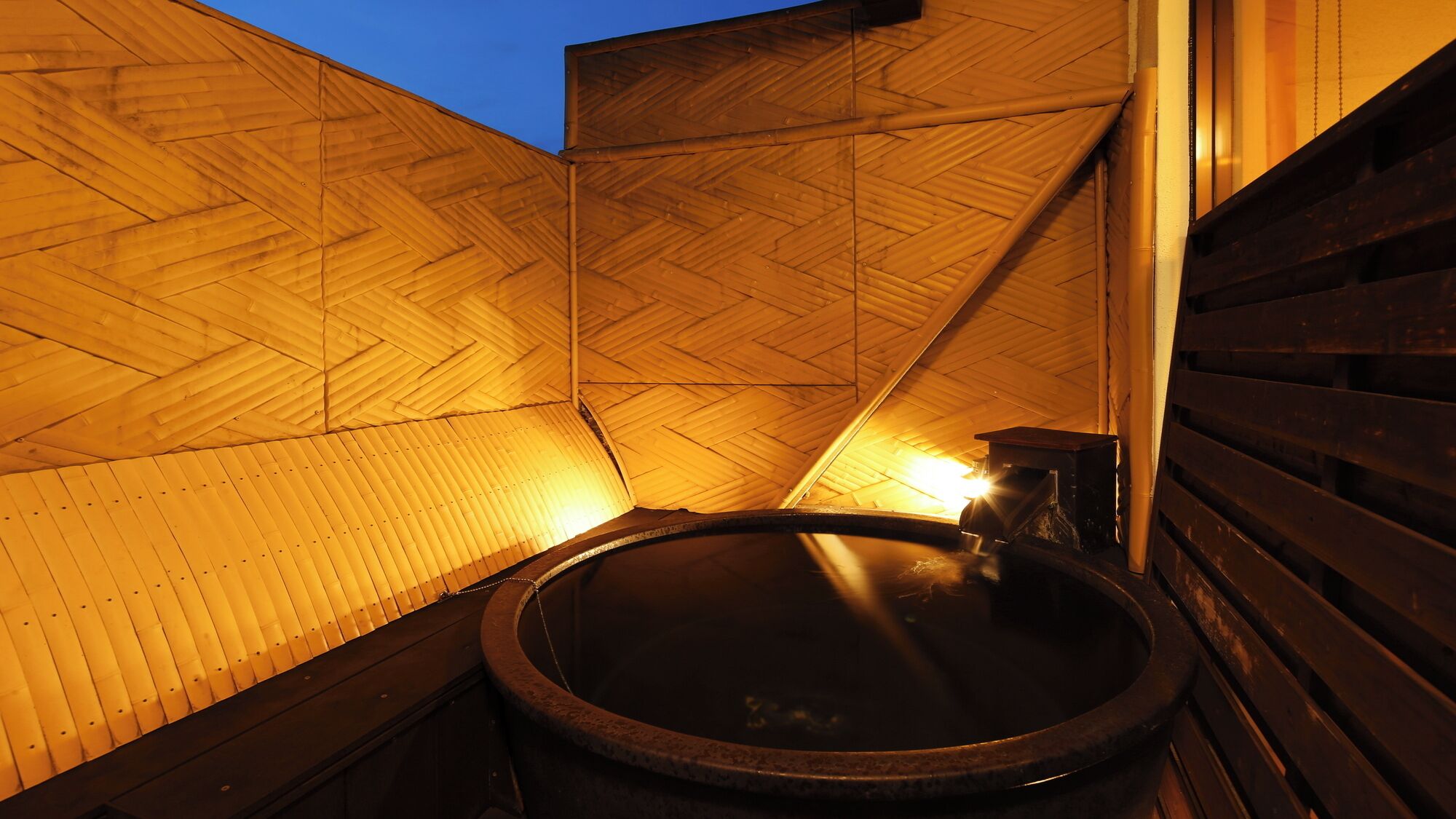 A wooden interior with a hot tub and a wooden slatted wall.