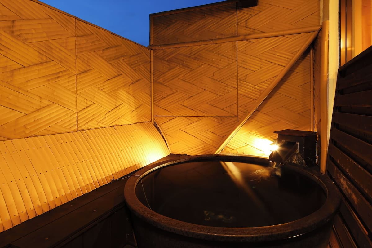 A wooden interior with a hot tub and a wooden slatted wall.