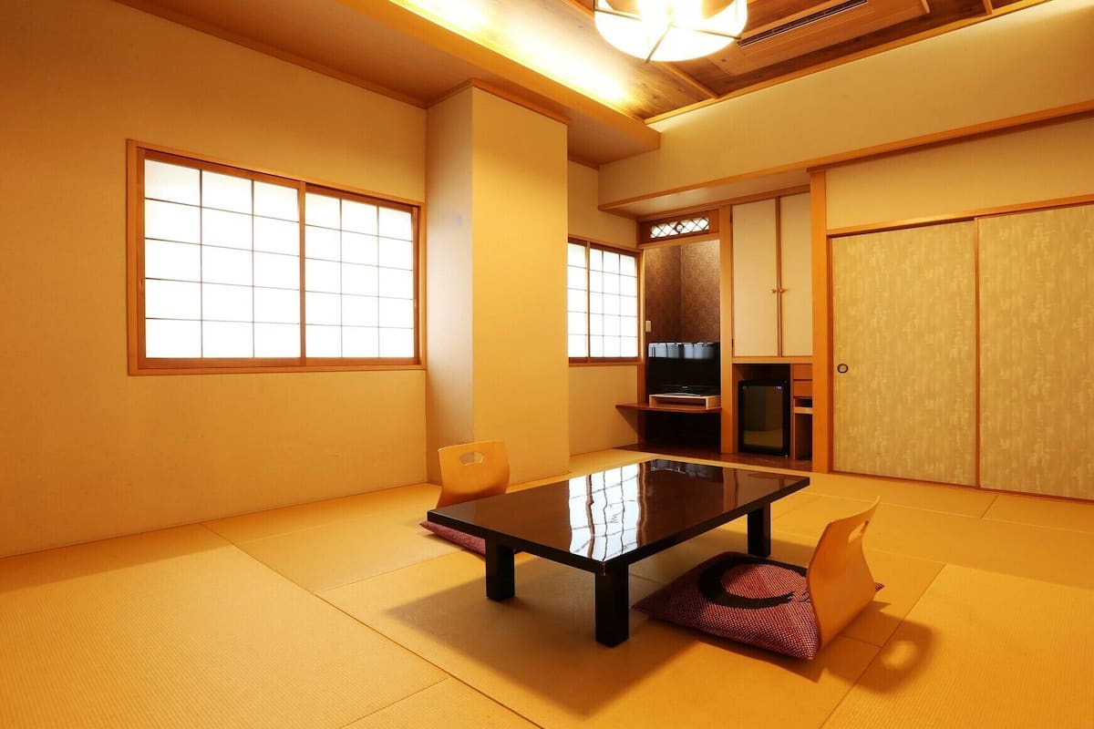 A traditional Japanese room with tatami flooring, a low table, and sliding doors.