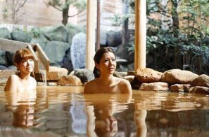 A hot spring bath area with large rocks and wooden structures. - Arima Royal Hotel (Kobe)