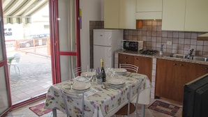 A kitchen with a dining area, a refrigerator, a microwave, and a tiled backsplash. - Casa Parago (Alghero)