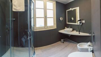 A modern bathroom with a glass-enclosed shower, a sink with a mirror, and a toilet.