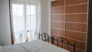Une chambre à coucher avec un lit, une armoire en bois et une fenêtre ornée de rideaux légers.