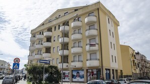 Un immeuble à plusieurs étages doté de balcons, un panneau indiquant un passage piéton et un panneau indiquant la limite de vitesse.