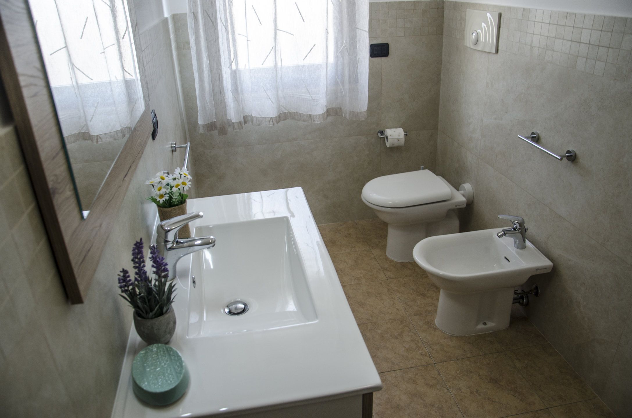 Ein Badezimmer mit Waschbecken, Toilette, Bidet und Spiegel.