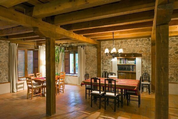Enjoy meals in this charming dining area with a long wooden table, fireplace, and bookshelf.