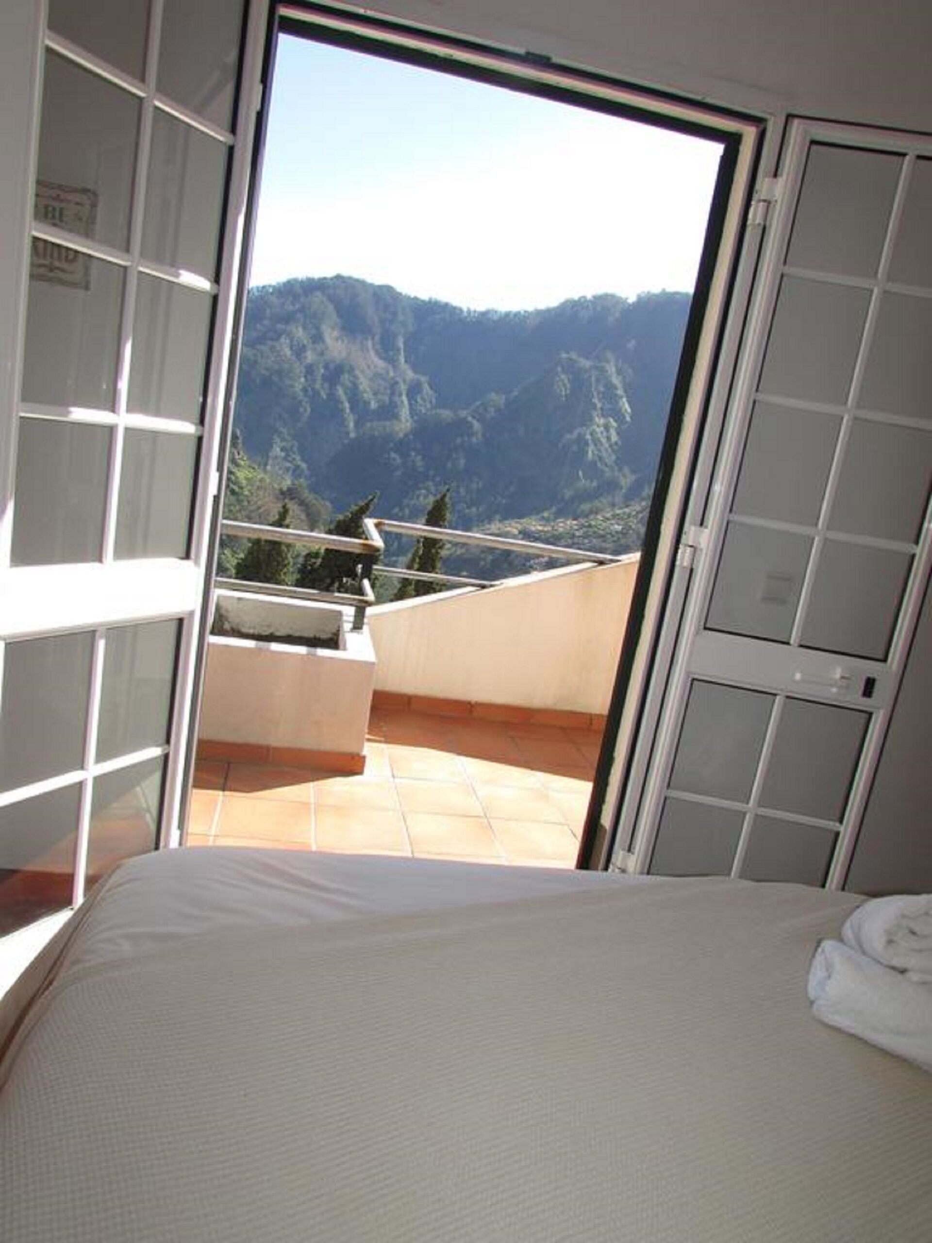 Une chambre à coucher avec un lit, une vue sur les montagnes et un balcon doté d’une balustrade.