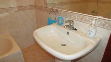 A bathroom with a white sink, a blue towel, and a bottle of hand sanitizer.