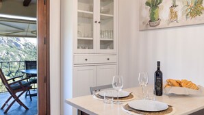 A dining area with a table set for two, a cabinet with glass doors, and a painting on the wall. - Porto Cervo Villa La Gjanda, surrounded by nature, private heated pool (Arzachena)