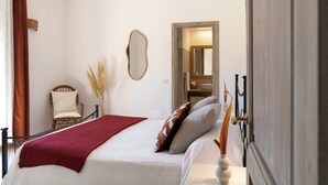 A bedroom with a bed, a chair, a mirror, and a door. - Porto Cervo Villa La Gjanda, surrounded by nature, private heated pool (Arzachena)
