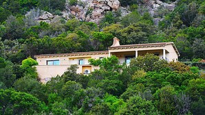 A building with a flat roof, surrounded by dense green foliage and rocky terrain. - Porto Cervo Villa La Gjanda, surrounded by nature, private heated pool (Arzachena)