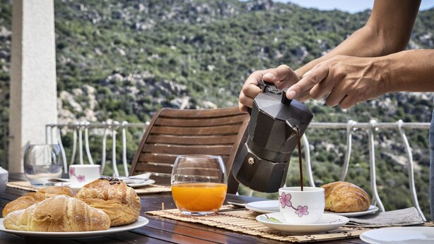A breakfast setting with croissants, orange juice, and coffee on a table with a scenic mountain view in the background. - Porto Cervo Villa La Gjanda, surrounded by nature, private heated pool (Arzachena)