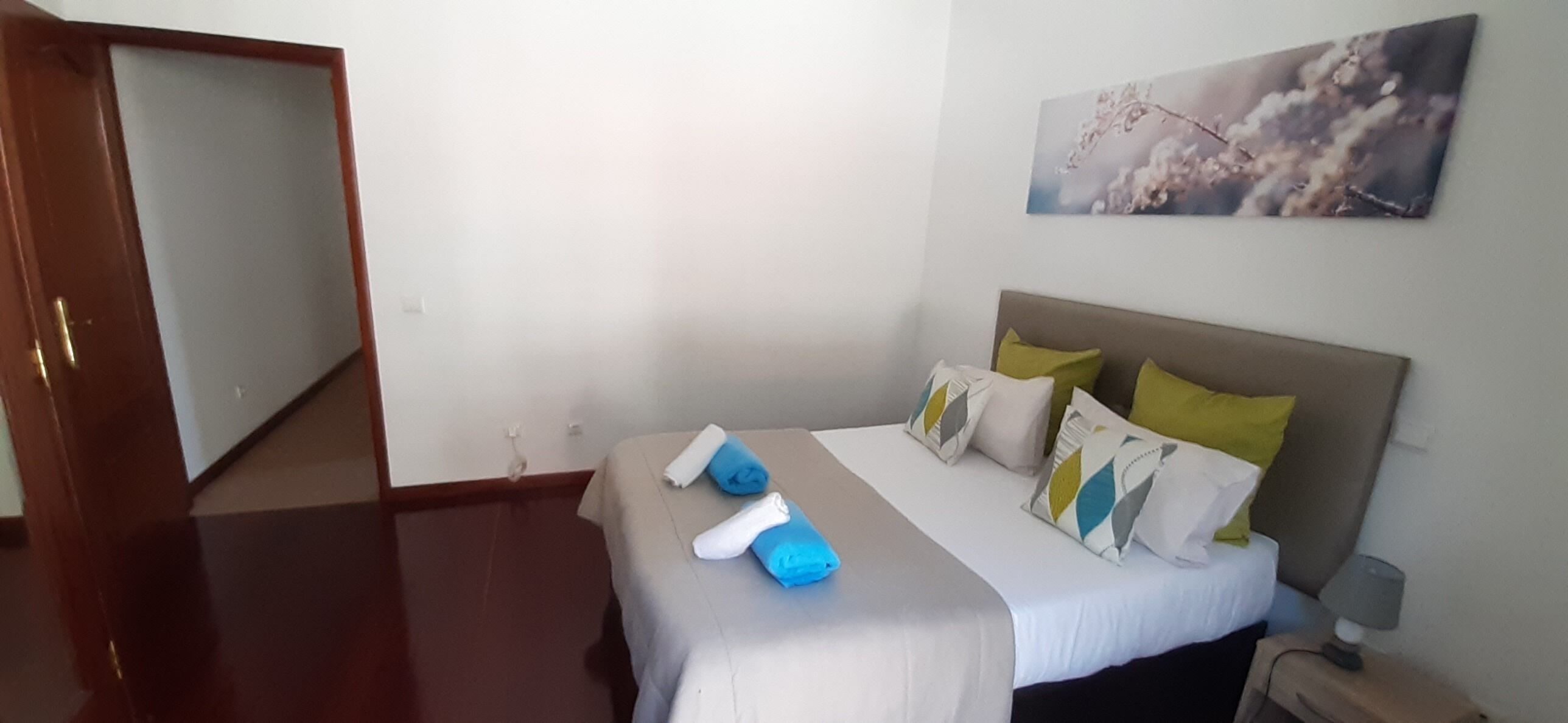 A neatly arranged bedroom with a bed, pillows, and a nightstand.