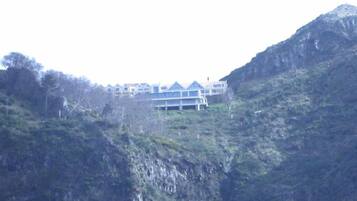 Un edificio de varios pisos con un estilo arquitectónico moderno, ubicado en una colina con vegetación densa.