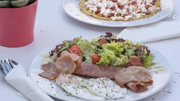 Un plato de comida con huevos, tocino y una ensalada.