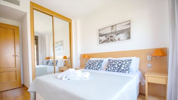 A hotel room with a large bed, a wardrobe, a bedside table, and a painting on the wall. - Waterfront Campezo (Madrid)
