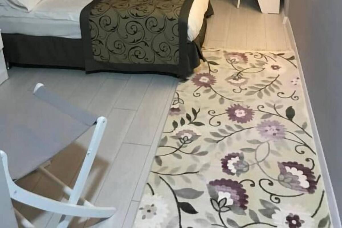 A bedroom with a bed, a chair, a desk, and a radiator.