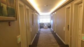 A hotel hallway with carpeted floors, doors on both sides, and a seating area at the end. - Grand Hotel Tesk (Ordu)